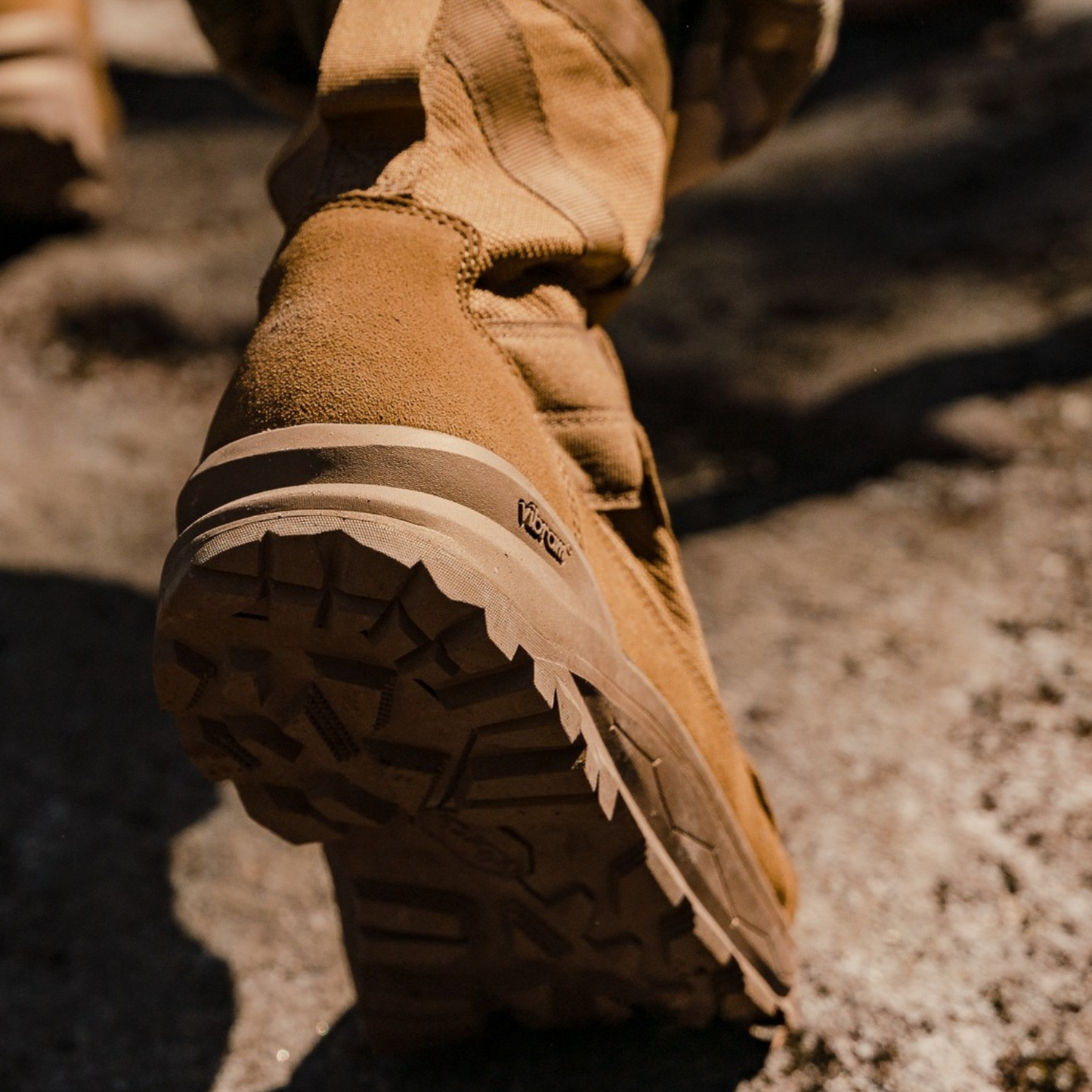 Coyote Brown Military Boot with a visible Vibram logo on a natural ground surface