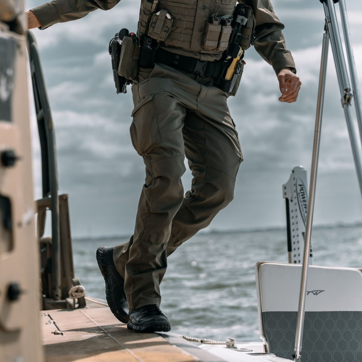 Officer in tactical gear and Oakley boots on a boat with water in the background