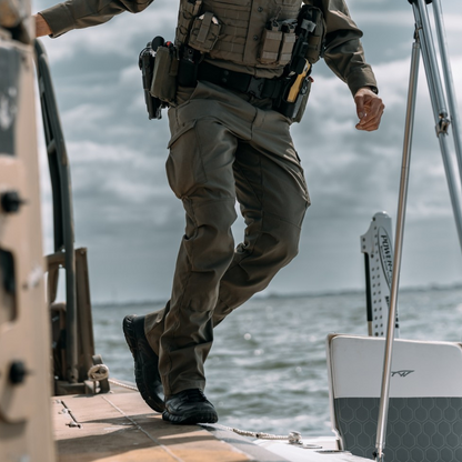 Officer in tactical gear and Oakley boots on a boat with water in the background